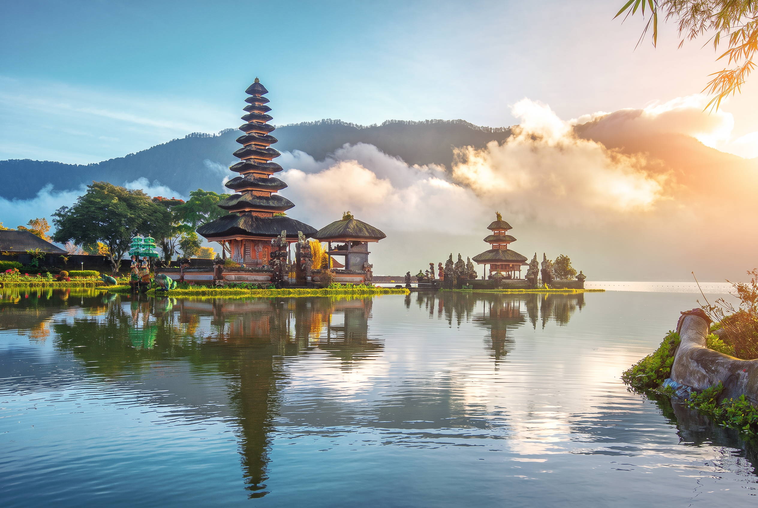 Ulun Danu temple reflected in a tranquil Bali lake beneath misty mountains at sunrise