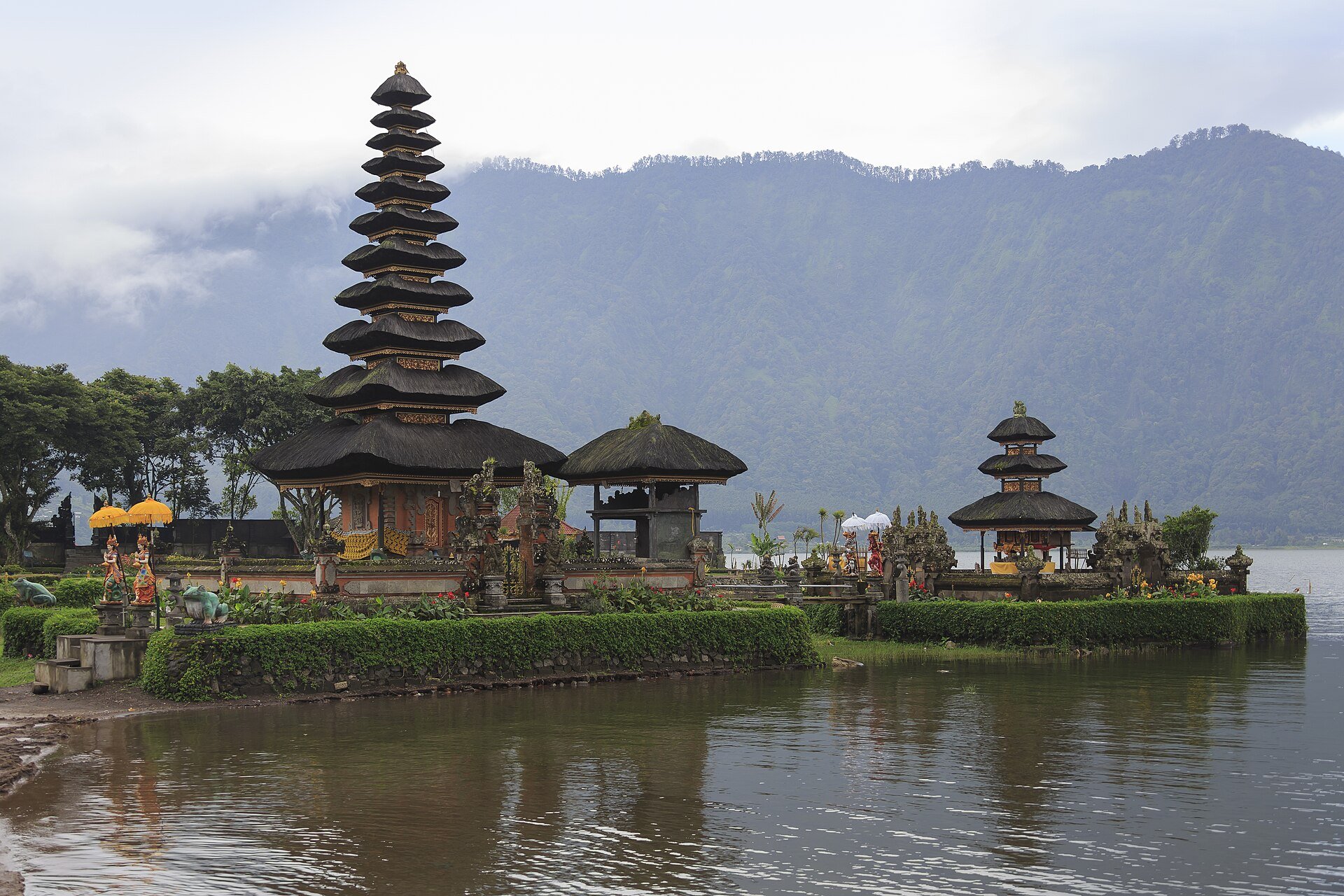 Ulun Danu temple reflected in a tranquil Bali lake beneath misty mountains at sunrise