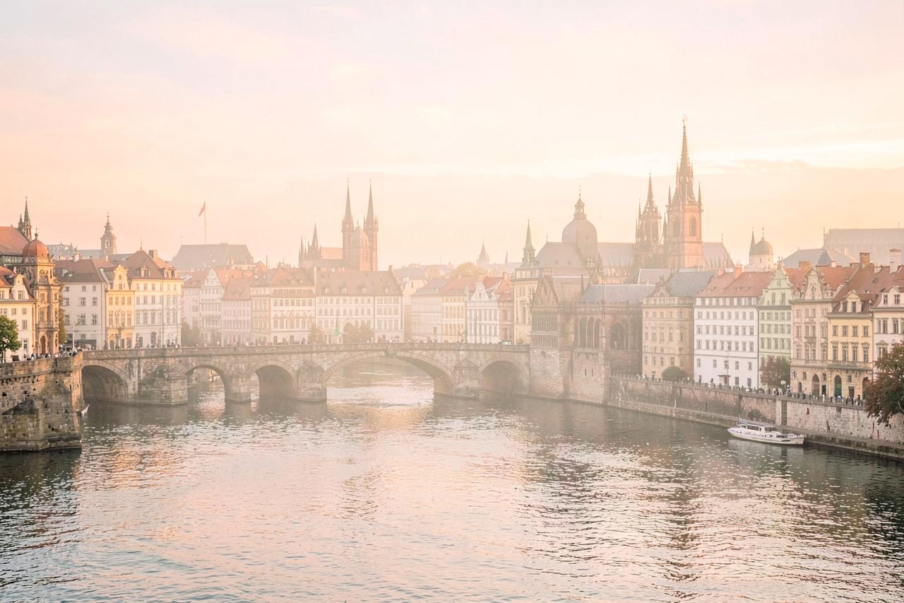 Prague old town spires and the Charles Bridge over the Vltava river in soft golden light